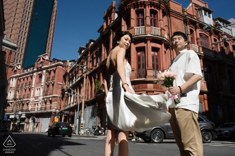 Bride-to-be's dress billows against the heritage brick wall of the Bund in Shanghai, China.