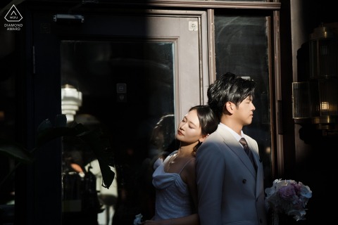 Sunlight illuminates an embracing couple's closeness in the shadow of a doorway on Shanghai's historic Bund.