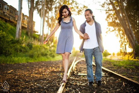 Santa Cruz engagement photo: a couple walks hand-in-hand on train tracks at sunset.