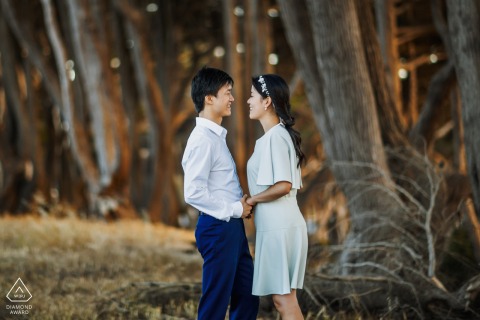 Couple's engagement portrait in San Francisco's forest: they pose eye to eye among the trees.