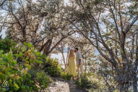 A couple shares a kiss on a lakeside pathway in South Lake Tahoe, California, in this engagement portrait.