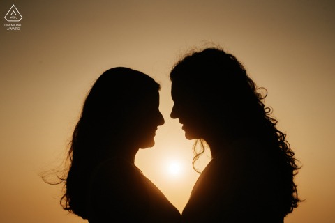 Silhouette portrait of a couple on Labruge beach, Leça, Porto, Portugal, facing each other while shaping a heart against the warm-toned sunset backdrop.