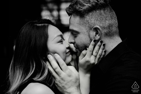 New York engagement photo session: Central Park black-and-white portrait. Tight close-up shot of the couple face-to-face, grabbing each other's faces for dramatic effect.