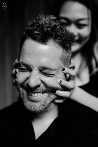 New York City engagement photography: Central Park black-and-white portrait. Playful shot of the woman grabbing the man's face from behind. Candid and fun interaction.