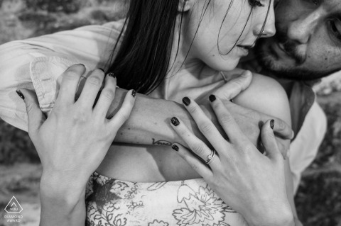 Black And White Intimacy In Baeza: A Pre-Wedding Embrace A tight black-and-white portrait of a pre-wedding couple in Baeza, Jaén. The photograph emphasizes their intimacy as the groom-to-be gently wraps his arms around his fiancée from behind in a close embrace.