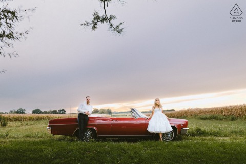 In Gambrills, Maryland, this sunset portrait shows the couple standing on opposite sides of a red convertible vintage car—she by the front tire and he by the rear—creating a stylish and balanced composition.