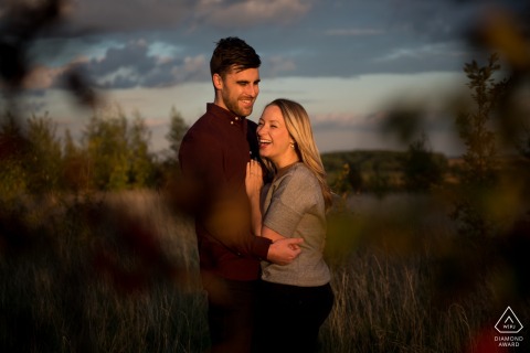 This beautiful Nomansland, Hertfordshire portrait captures the bride and groom-to-be laughing genuinely, bathed together in the warm light of the fading evening, symbolizing their shared joy.