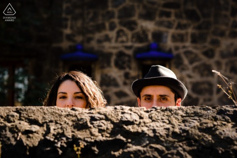 This playful Mexico City portrait captures the couple's fun heads peeking just above a stone wall, with only their eyes showing, creating a whimsical and unique composition.