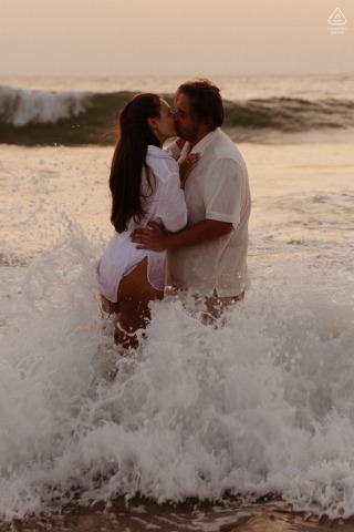This dramatic vertical portrait from Labenne, France, captures a kiss during a sunset swim, with the couple embracing as crashing waves break around them in the warm, fading light.