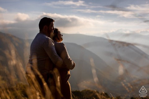 This scenic portrait at La Pierre Percée, France, captures the couple watching the sunset from a high overlook, as he warmly embraces her from behind, sharing a peaceful and expansive view.