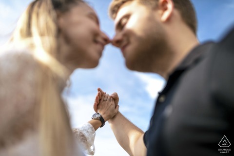 In Budapest, a low camera angle focuses on the couple's held hands overhead, emphasizing their promise under an endless sky, with a shallow depth of field framing their smiles.