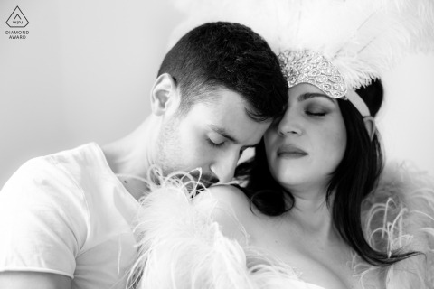 Tender Shoulder Kiss in Window Light at Private Atelier Ravenna Couple Portrait Session This stunning black and white portrait from a private atelier in Ravenna, Italy, captures an intimate scene as the couple stands in the window light; she wears fancy clothes, both have eyes closed, and he tenderly kisses her shoulder.