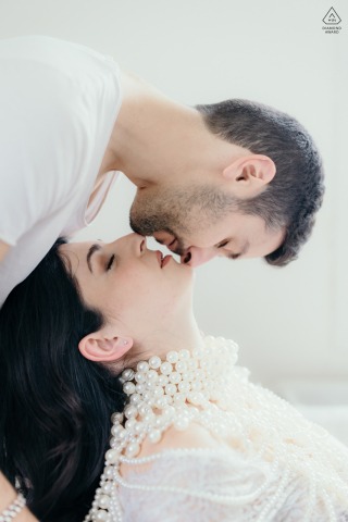 Yin Yang Kiss in Private Atelier Ravenna Candid Couple Portrait Session In a private atelier in Ravenna, Italy, a candid love session captures her tilting her head back as he stands behind, kissing her upside down in a yin-yang pose.