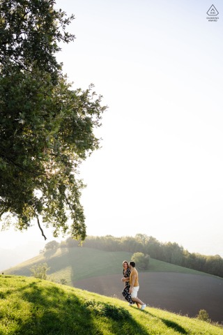 In Venon en Isère, France, a couple is captured sprinting up the hill toward the iconic Chêne de Venon, photographed from a vibrant, vertical perspective.
