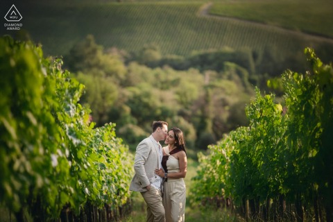 In the lush Sienese vineyards of Tuscany, a couple is symmetrically framed by vibrant greenery, highlighting the scenic beauty of this breathtaking location.