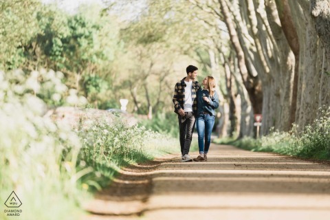 Along the Canal du Midi in Toulouse, France, the couple walks closely together on a sun-dappled trail beneath the trees, enjoying a peaceful promenade.