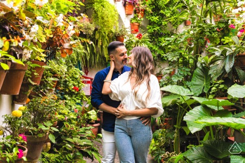 In Vejer de la Frontera, Cádiz, Spain, a pre-wedding portrait shows him wrapping her from behind, about to kiss, surrounded by lush green foliage.