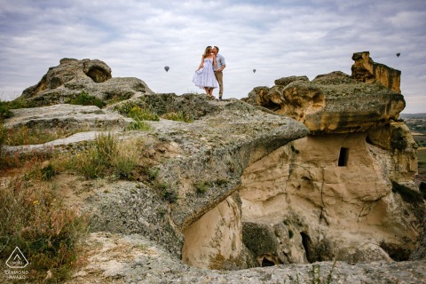 In Göreme, Nevşehir, Turkey, a Cappadocia pre-wedding photo captures the couple perched atop ancient cave dwellings, surrounded by the breathtaking landscape of the Old World.