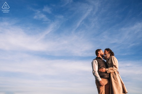 At Chapelle Saint-Aubin in France, the couple is staged with minimalist framing beneath a vast blue sky and wispy clouds, highlighting the serene setting.