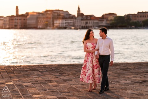 Engaged Couple Walking on San Giorgio Island With Venice Cityscape On San Giorgio Island in Venice, Italy, the couple walks together with the iconic cityscape of Venice beautifully visible in the background.