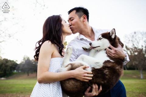 In Saratoga, CA, an engagement portrait captures the couple sharing a kiss while he lovingly holds their dog in his arms.