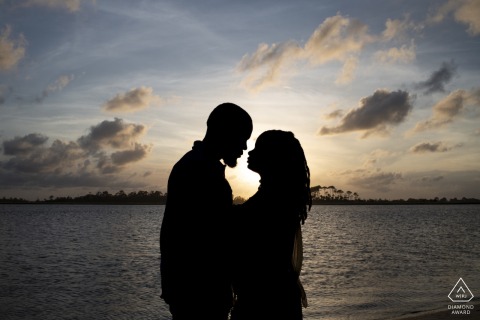 At Tybee Island, Georgia, an engaged couple poses face to face in silhouette during a sunset portrait session.
