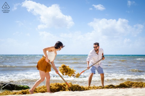 In Playa del Carmen, a couple plays on the beach with seaweed, using pitchforks, for a lighthearted portrait.