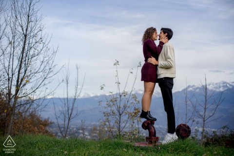 In Grenoble, France, a woman stands on a park sculpture to reach up and kiss her partner for a playful couple’s portrait.