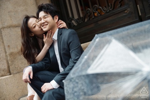 At the Bund in Shanghai, China, a woman kisses her partner’s cheek as they both smile for a portrait.