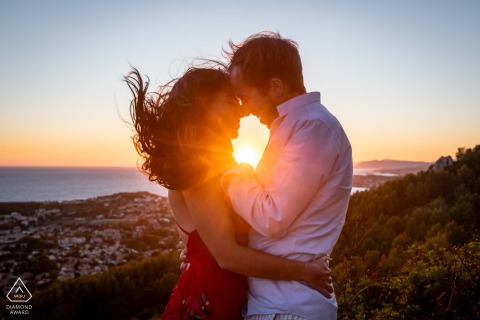 At Six-Fours-les-Plages in Var, Provence, France, a couple kisses at the top of a hill during sunset, center framed for a portrait.