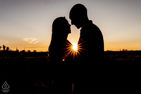 Silhouetted against a sunburst in Parque Villarino, Argentina, the couple stand in profile for a pre-wedding portrait, the look enhanced using a filtered lens.