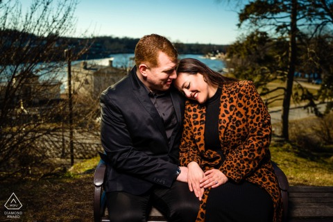 At Fairmount Waterworks in Philadelphia, a couple sits embracing outdoors, leaning into each other for a portrait illuminated by on-location lighting.