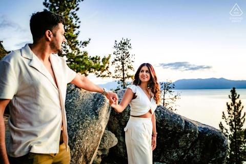 South Lake Tahoe Engagement Portrait: Couple Holding Hands by Lake Standing on the shore of South Lake Tahoe, California, two people hold hands and make eye contact, with the lake visible in the background.