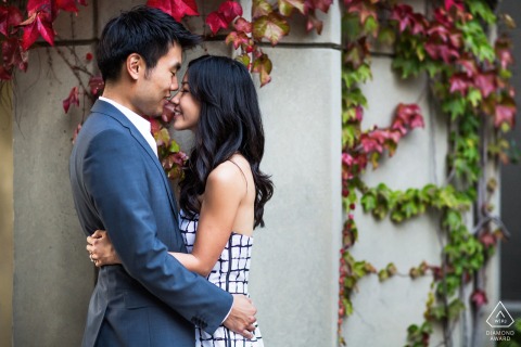 An engaged couple stands nose to nose in profile in a garden setting during a portrait session at UC Berkeley in California.