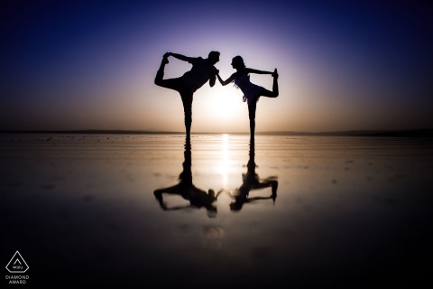 A silhouetted engaged couple poses in a mirrored, ballet-inspired dance stance during an engagement session at Tuz Gölü in Şereflikoçhisar, Turkey, with the sunset glowing behind them.