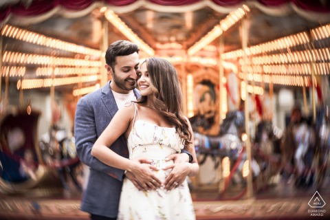 Couple Embracing Before Florence Carousel, Swirly Petzval Bokeh Black And White A couple stands embracing in front of Florence’s historic carousel, center framed, with the Petzval lens creating signature swirly bokeh for a whimsical and romantic black and white portrait.