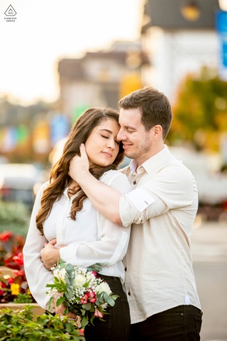 Newlyweds in Gramado, Brazil, celebrate their destination engagement shoot as she holds a bouquet of flowers and he gently cradles her face with his hand, capturing their affection.