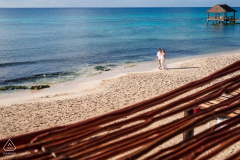 Couple walking along a deserted beach at Viceroy Mexico Riviera Maya, photographed from a slight elevation to create a minimalist composition emphasizing the vast, tranquil shoreline and serene atmosphere.