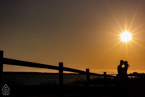 Framed by golden sunset light near Nobska Lighthouse, Falmouth, MA, the couple shares a quiet kiss by the water, capturing the intimacy and natural beauty of a Cape Cod engagement session.