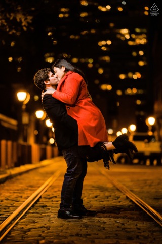 Golden lights illuminate the city streets of Philadelphia as the couple stands together in a tall vertical portrait, the vibrant scene creating an intimate atmosphere just for them.