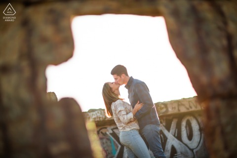 Engagement portrait of a couple framed by weathered concrete ruins at the edge of the water at San Francisco’s historic Sutro Baths, sharing a quiet, affectionate kiss.