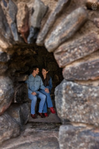 A rustic stone window at Little Park in Idledale, Colorado, provides a unique glimpse of an engaged couple enjoying life together while exploring the beautiful and scenic outdoors.