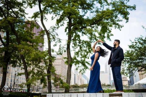 A joyful groom-to-be twirls his bride-to-be at Grant Park in Chicago, Illinois, celebrating their engagement with a spirited and energetic movement within the heart of the scenic public park.