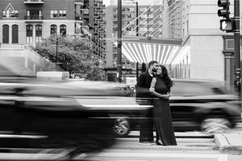 Cars whiz past the couple on Michigan Avenue in Chicago, Illinois, as they share an intimate connection amidst the fast-paced energy and urban landscape of the busy city streets.