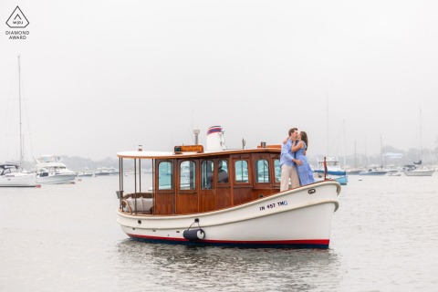 This adventurous couple stands together on the bow of a boat during their engagement session aboard the Nantucket Tug Boat, surrounded by the scenic waters of Nantucket Harbor, Massachusetts.