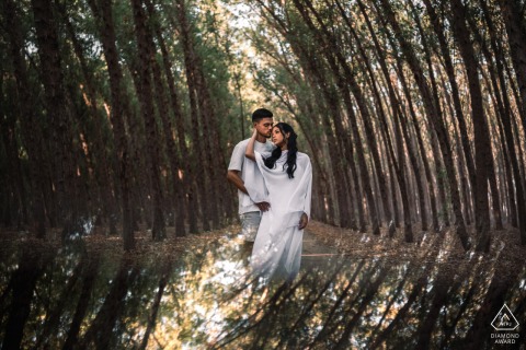 The couple is captured amidst a towering forest of eucalyptus trees with a beautiful reflection at Mar de Eucaliptos, Alagoas, highlighting the serene and natural beauty of their engagement.