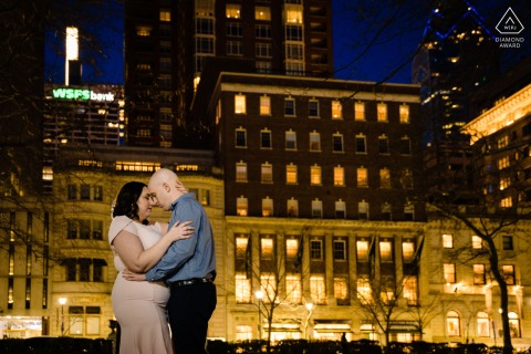 A couple shares a quiet embrace beneath the glowing city lights of Rittenhouse Square in Philadelphia, Pennsylvania, where the rest of the world falls away during their intimate evening portrait.