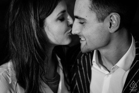 She shares a playful and affectionate interaction as she kisses him on the nose during their romantic engagement portrait session in the charming and historic city of Gorizia, Italy.