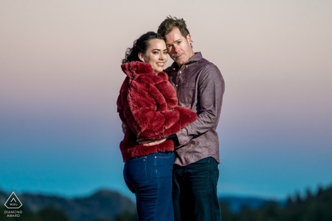 In the glow of sunset in Rocky Mountain National Park, Colorado, the couple stands side by side, their embrace framed by dramatic peaks and the last rays of daylight for a peaceful, tender portrait.