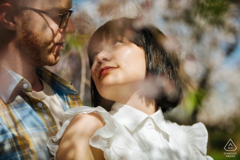 Through a blur of spring flowers in a Bronx venue in New York, a couple is seen sharing a quiet gaze, their love framed by the fresh blooms and city landscape surrounding them.